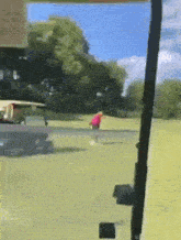 a person in a red shirt is playing golf on a golf course .