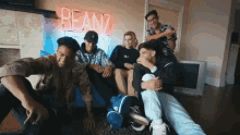 a group of people are sitting under a neon sign that says bean7