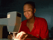 a man wearing a red shirt is using a sewing machine