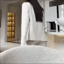 a woman with long black hair is standing in a room .