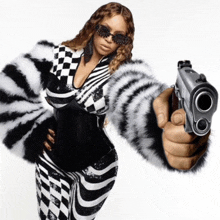 a woman wearing a fur coat and sunglasses is holding a gun