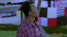 a man in a plaid shirt stands in front of a man laksa banner