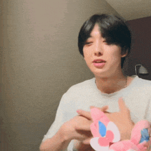 a man in a white shirt is holding a pink and blue flower