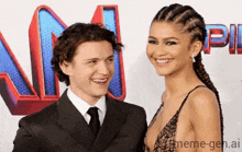 a man and woman are standing next to each other on a red carpet and smiling .