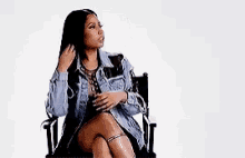 a woman is sitting in a chair with her legs crossed and holding her hair .