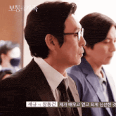 a man in a suit and tie is standing next to another man