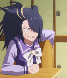a girl with black hair is sitting at a desk with her fist in her hand