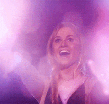 a woman with her arms outstretched in front of a purple light