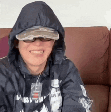 a man wearing a hooded jacket and a hat is smiling
