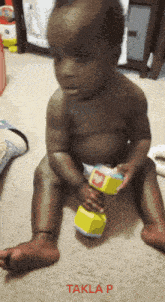 a baby is sitting on the floor playing with a toy and the name takla p is on the bottom of the picture