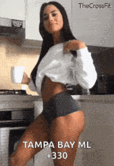 a woman is standing in a kitchen holding a cup of coffee and the words tampa bay ml 330 are visible