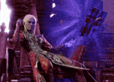 a man in a red robe sits on a throne in front of a purple object