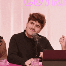 a man in a black sweater is smiling in front of a microphone that says rode