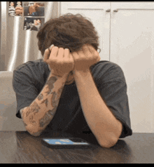 a man sitting at a table with his hands on his face