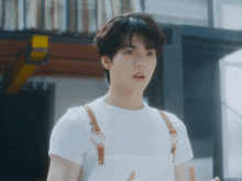 a young man wearing overalls and a white t-shirt