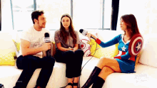 a woman in a captain america costume is sitting on a couch talking to two people .