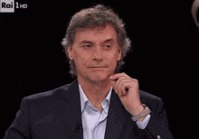 a man wearing a suit and a watch is on rai 1 hd