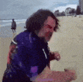 a man in a blue shirt is standing on a beach .