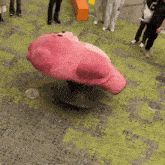 a group of people are standing around a pink stuffed animal