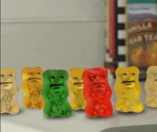 a row of gummy bears with faces on them are on a counter .