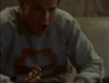 a man wearing a rolling stones sweatshirt is eating a pizza
