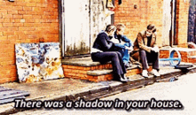 three people are sitting on the steps of a brick building with the words there was a shadow in your house