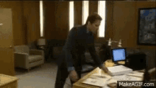 a man in a suit is standing in front of a desk with papers on it .