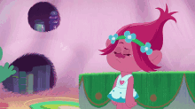 a troll with flowers in her hair is standing in front of a pink wall