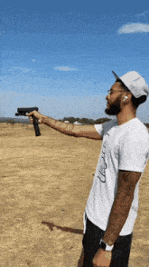 a man is holding a gun in a field with a blue sky in the background