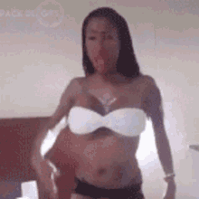a woman in a white bikini top is standing in front of a bed