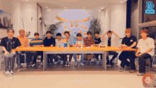a group of young men are sitting around a table with a happy birthday banner behind them
