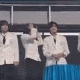 a group of men in white suits are standing in front of a table .