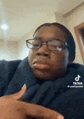 a woman wearing glasses is making a funny face while sitting in a chair .