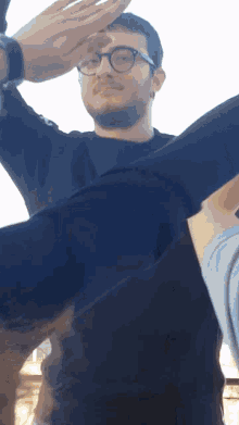 a man wearing glasses and a black shirt is being held by another man