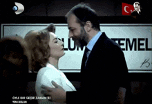 a man and a woman kiss in front of a sign that says temel