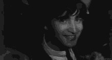 a black and white photo of john lennon making a funny face .