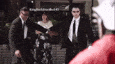 a man in a suit is standing next to a woman in a floral skirt .
