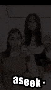 two girls are standing next to each other with the word aseek on the bottom right