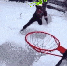 a person playing basketball in the snow with a green frog in the background