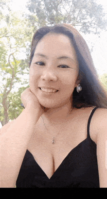 a woman wearing a black tank top and earrings smiles