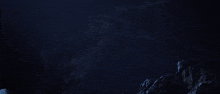 a person laying on a rock in the dark with a blue background
