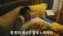 a man is laying in bed with a yellow comforter and a laptop on the nightstand