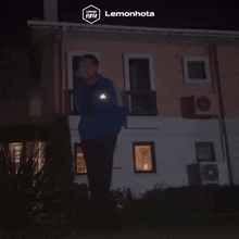 a man in a blue jacket stands in front of a building that says lemonhota on the bottom