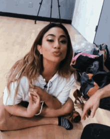 a woman in a white shirt is sitting on the floor with her legs crossed
