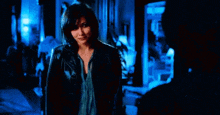 a woman in a leather jacket is standing next to a man in a room .