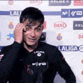 a man wearing a laliga shirt stands in front of a wall of ads