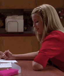 a woman in a red shirt sits at a desk in front of a file holder that says mexico