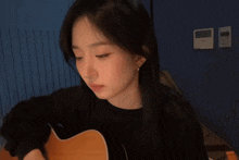 a woman is playing a guitar in a dark room