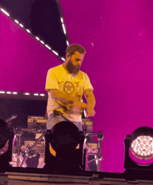 a man in a yellow shirt with a star on it stands in front of a purple background