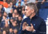 a man in a blue shirt is clapping in front of a peacock advertisement